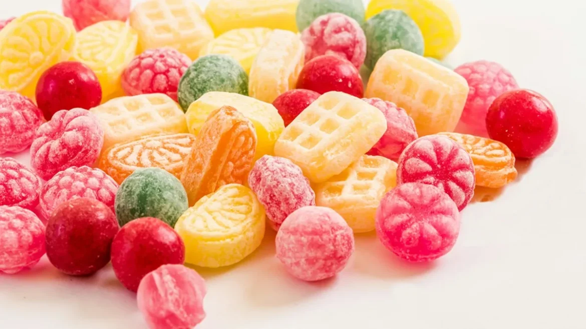 Imagem em 1200 x 675 de doces coloridos e variados, como jujubas e balas, sobre uma superfície branca, simbolizando o que significa sonhar com doces e explorando seus significados vibrantes.